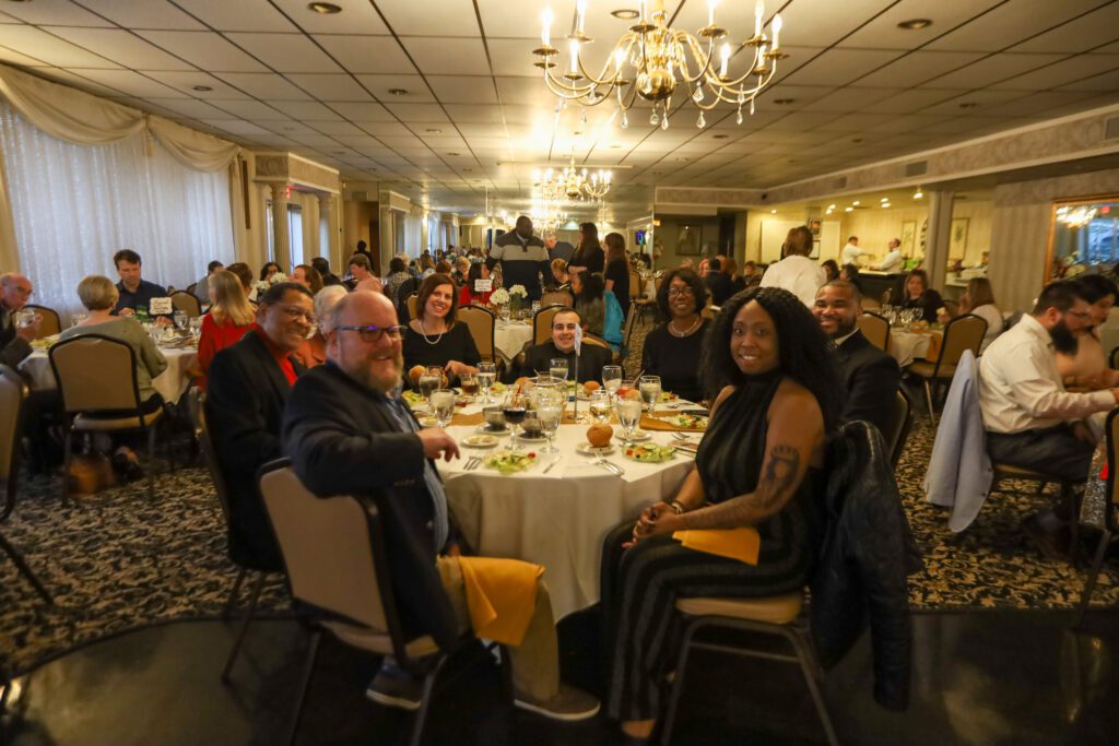 A diverse group of people at dinner tables at the fundraising event